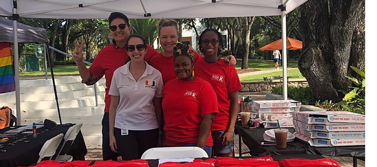 GradOut students underneath a tent, smiling at the camera.